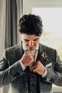 Bräutigam in grauem Anzug mit liebevollem Anstecker von Ganz Unverblümt in Niederbayern