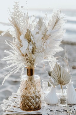 Goldene Vase mit natürlichen Trockenblumen im Bohostil