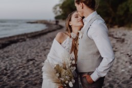 Braut und Bräutigam mit natürlichem Brautstrauß von Ganz Unverblümt am Strand
