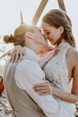Braut und Bräutigam küssen sich vor Triangle Traubogen von Ganz Unverblümt