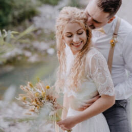 Braut und Bräutigam lachen sich an mit natürlichem Brautstrauß von Ganz Unverblümt