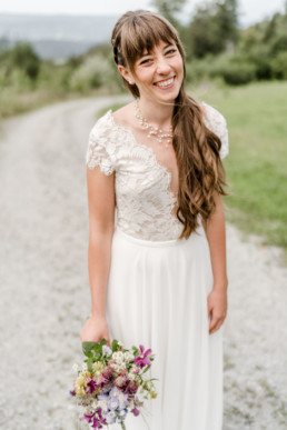 Braut lacht mit Blumenstrauß von Ganz Unverblümt in der Hand in die Kamera