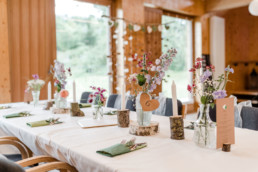 Tisch mit Baumscheiben und Vasen gefüllt mit bunten Blumen von Ganz Unverblümt