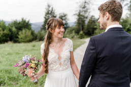 Braut und Bräutigam lächeln sich an mit Blumenstrauß von Ganz Unverblümt