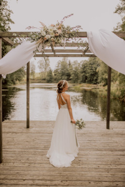 Braut vor Schönsee mit Gesteck und Strauß von Ganz Unverblümt