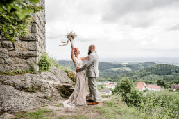 Braut und Bräutigam freuen sich vor Aussicht der Burg Brennberg