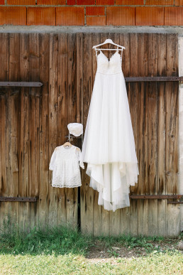 Brautkleid und Kinderkleind hängen an Scheune