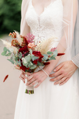 Braut hält Brautstrauß in Rot Grün in den Händen