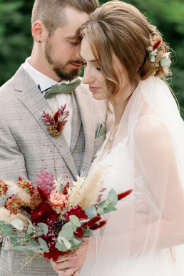 Braut und Bräutigam mit Strauß Anstecker und Haarblumen von Ganz Unverblümt