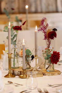 Rustikal dekorierter Tisch mit goldenen Kerzenständern Vasen und Baumscheiben von Ganz Unverblümt