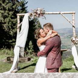 Brautpaar vor Birken Traubogen mit Blumenschmuck von Meisterfloristik Ganz Unverblümt