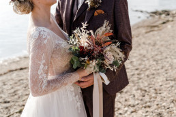 Braut und Bräutigam küssen sich mit natürlichem Brautstrauß von Ganz Unverblümt