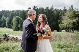 Braut und Bräutigam lächeln sich an mit natürlichem Strauß von Ganz Unverblümt