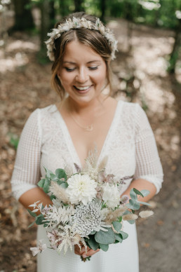 Braut glücklich mit natürlichem Blumenkranz und Strauß