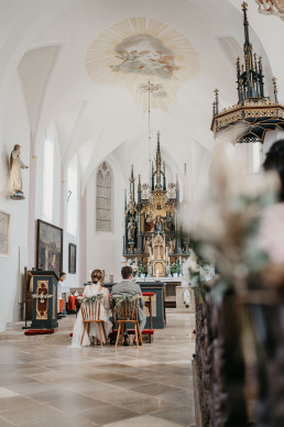 Brautpaar in Kirche mit Bank- und Stuhlschmuck von Ganz Unverblümt