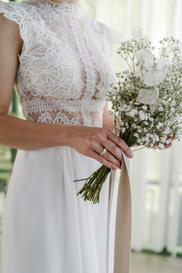 Braut hält natürlichen Brautstrauß von Ganz Unverblümt in Weißtönen in Händen
