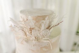 Hochzeitstorte mit minimalistischen Trockenblumen in weiß von Ganz Unverblümt