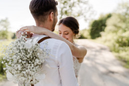 Braut und Bräutigam umarmen sich mit Strauß in natürlichen Tönen