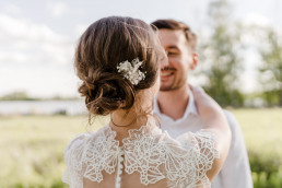 Braut und Bräutigam umarmen sich mit natürlichem Haarschmuck von Ganz Unverblümt