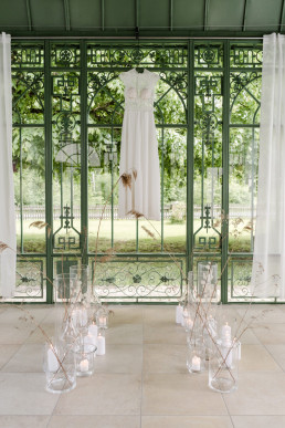 Hochzeitskleid hängt hängt vor Windlichtern und Trockenblumen von Ganz Unverblümt