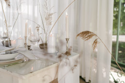 Minimalistisch gedeckter Tisch mit Dekoartikeln und Blumen von Ganz Unvebrlümt