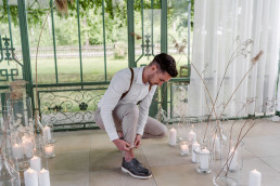 Bräutigam richtet sich die Hose vor Windlichtern und Kerzen von Ganz Unverblümt