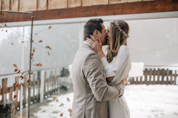 Braut und Bräutigam küssen sich vor winterlichem Aufbau einer freien Trauung