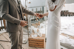 Braut und Bräutigam halten Händchen vor Deko mit Holzkisten und Windlichtern von Ganz Unverblümt