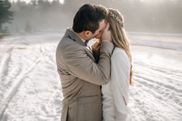 Braut und Bräutigam küssen sich im Schnee