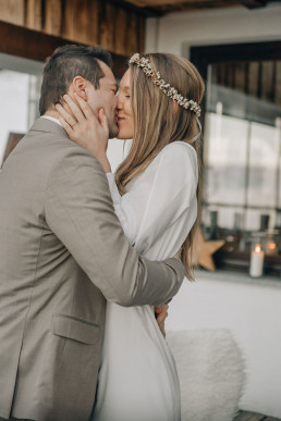 Braut und Bräutigam küssen sich mit Haarkranz von Ganz Unverblümt