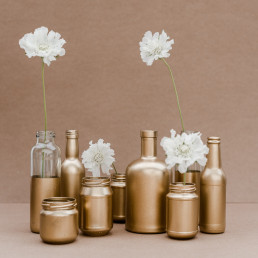 Gold besprühte Marmeladengläser mit weißen Blüten für Tischdekoration zur Hochzeit in Niederbayern