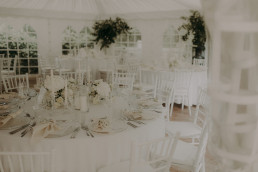 Eingedeckte Tische mit komplett weißen Gestecken und Windlichtern von Ganz Unverblümt