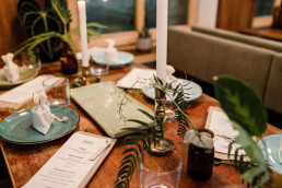 Eingedeckter Tisch in Gold Grün mit Blumen und Kerzen von Ganz Unverblümt