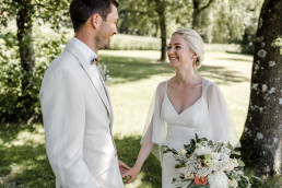 Braut und Bräutigam lachen sich an mit Brautstrauß von Ganz Unverblümt