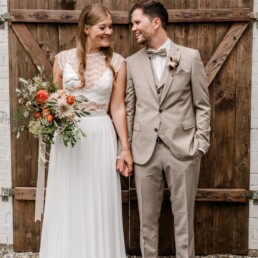 Brautpaar mit rostfarbenem Brautstrauß von Ganz Unverblümt beim Fotoshooting im Vierfalthof