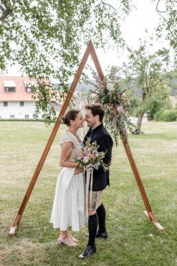 Braut und Bräutigam mit spitzem Traubogen dekoriert mit Wiesenblumen von Hochzeitsflorist Ganz Unverblümt