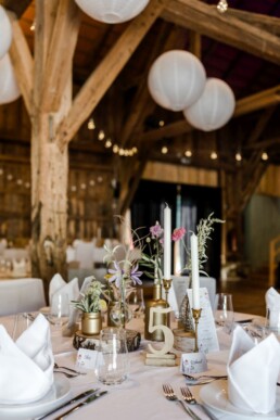 Rustikale Tischdekoration mit Wiesenblumen, Vasen und goldenen Tischnummern von Hochzeitsflorist Ganz Unverblümt