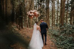 Brautpaar mit Luftballons beim Fotoshooting im Wald