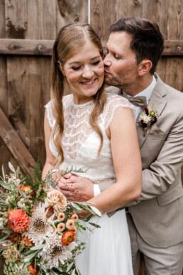 Küssendes Brautpaar mit Blumendekoration von Ganz Unverblümt beim Fotoshooting